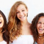 3 teenage girls smile, two without braces and one with braces who keeps her mouth clean