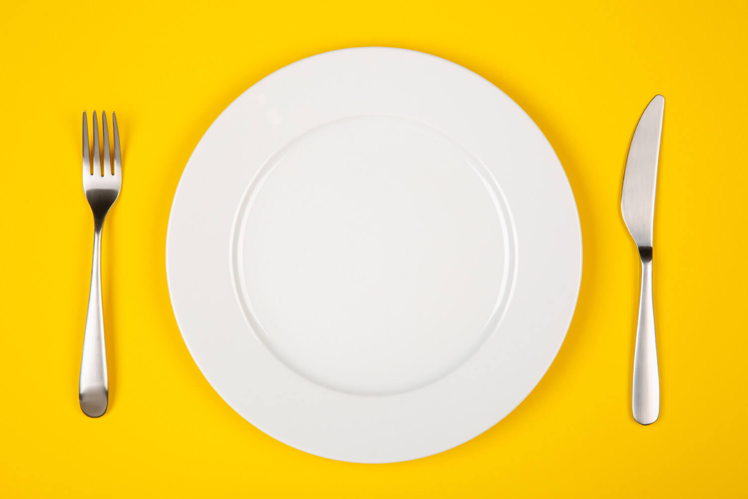 Aerial view of an empty place setting on a yellow background