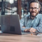 Adult business man with a laptop smiles while wearing braces as an adult