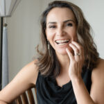 Middle-age woman in braces smiles while wearing a black tank top