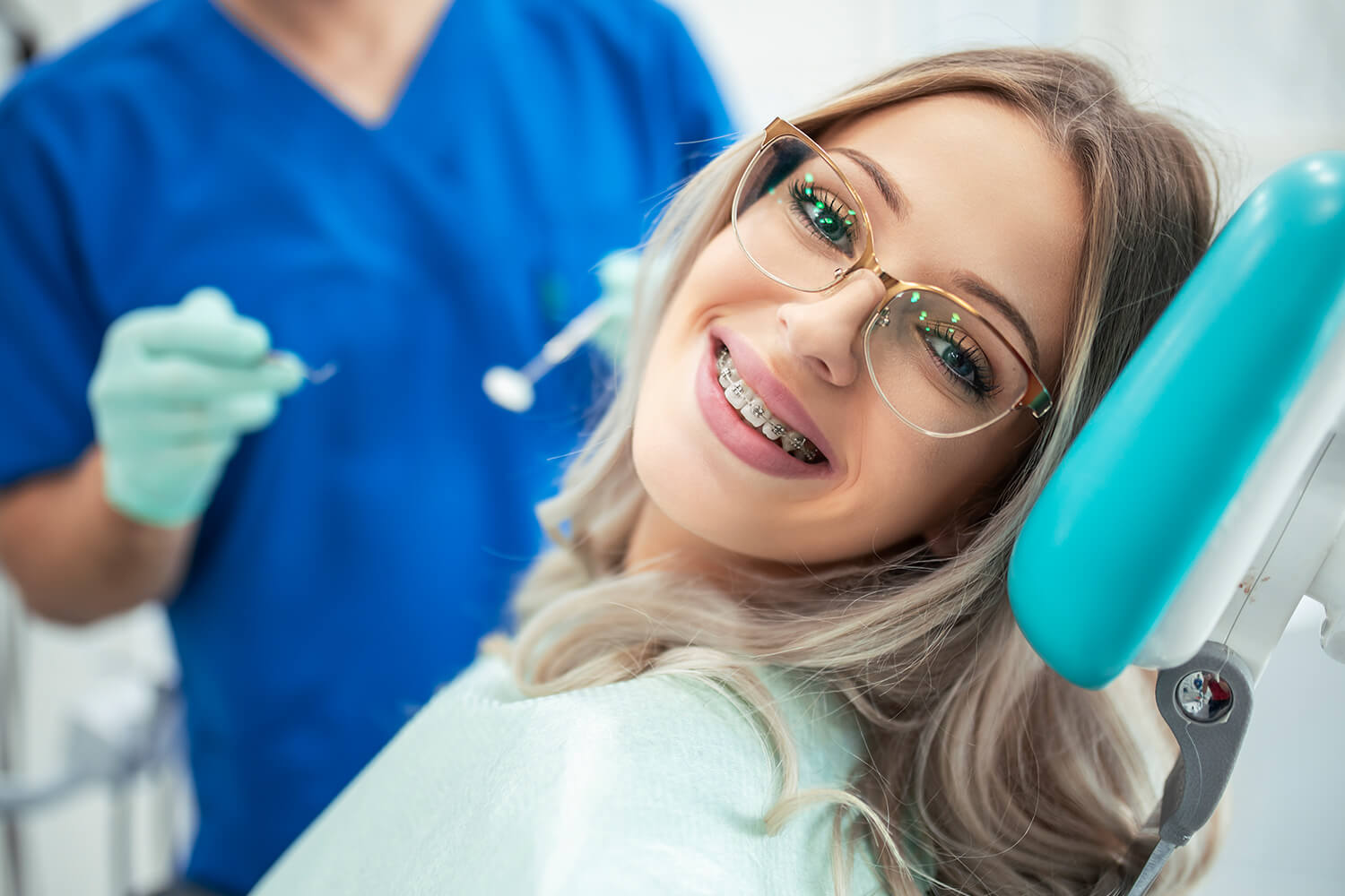 smiling girl with braces sitting in a dental chair