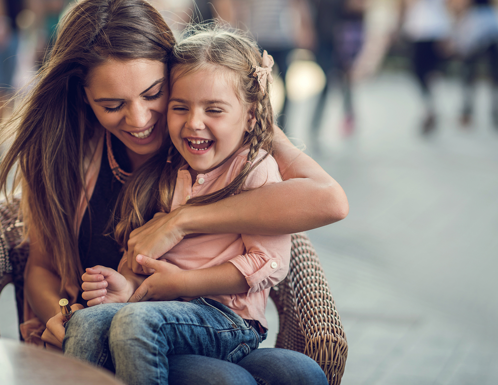 mom holding her young daughter on her lap