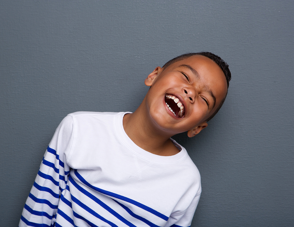 young boy laughing against gray background
